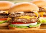 Stacked turkey cheeseburgers with lettuce, tomato, onion, and melted cheese on a soft bun.