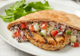 A pita stuffed with a Butterball Turkey Burger, tomatoes, cucumbers, onions, and tzatziki.  