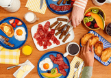 A table with several plates filled with breakfast foods.