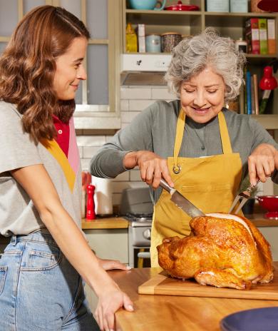 Grandmother and daughter carving a turkey